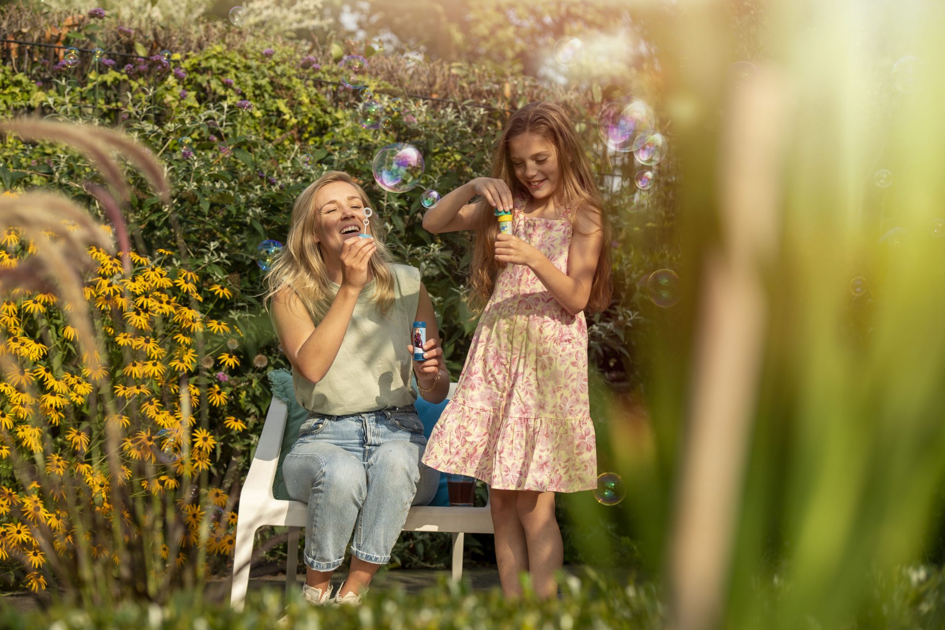 vrouw en meisje genieten van bellenblaas in een groene tuin
