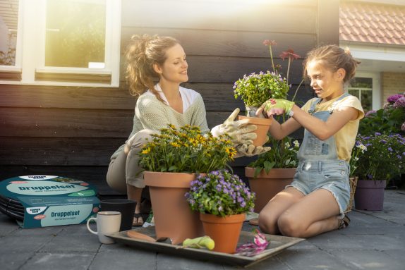 vrouw met meisje en een druppelset voor bloempotten